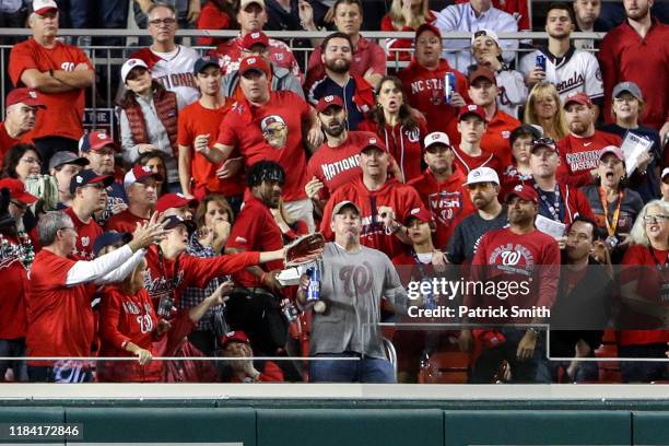 While holding two Bud Light beer cans, baseball fan, Jeff Adams, is hit in the chest with the home run ball hit by Yordan Alvarez of the Houston...