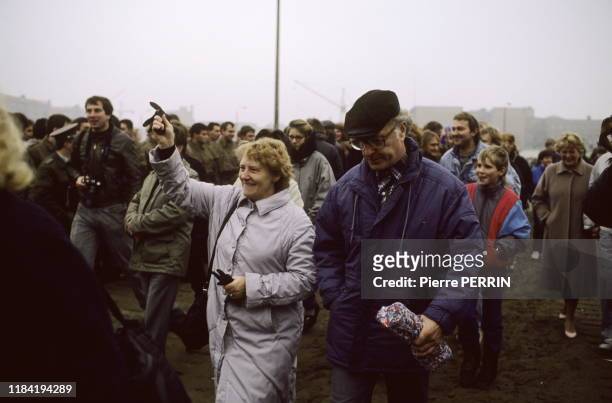 Couple berlinois Est-allemand joyeux dans la foule se pressant pour passer à l'Ouest à un check point après la chûte du mur de Berlin le 13 novembre...