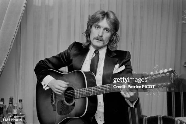 Le chanteur Christophe avec une guitare hez lui à Paris le 11 février 1974, France.