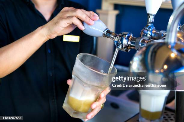 barman hands pouring a lager beer in a glass. - pulling stock pictures, royalty-free photos & images