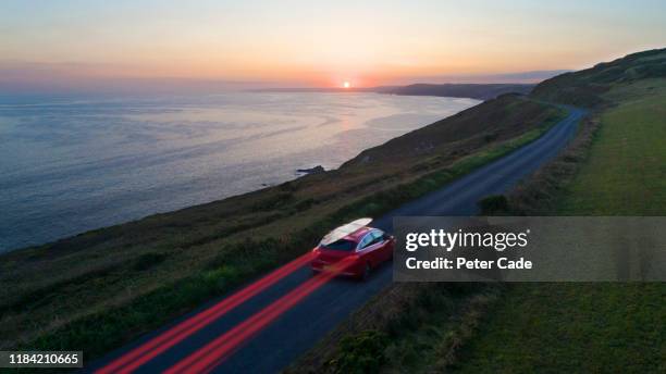 car driving along coastal road at sunset - sunset road stock pictures, royalty-free photos & images