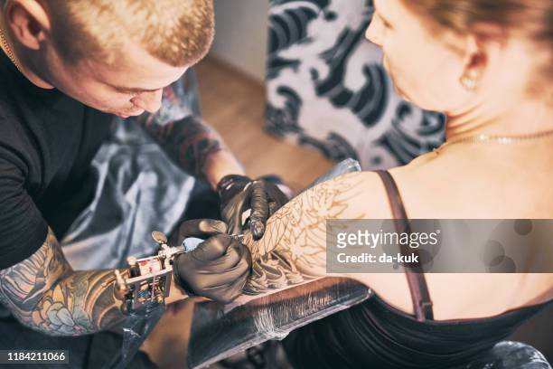 tattoo artist making a tattoo on a shoulder - tattoo shoulder stock pictures, royalty-free photos & images