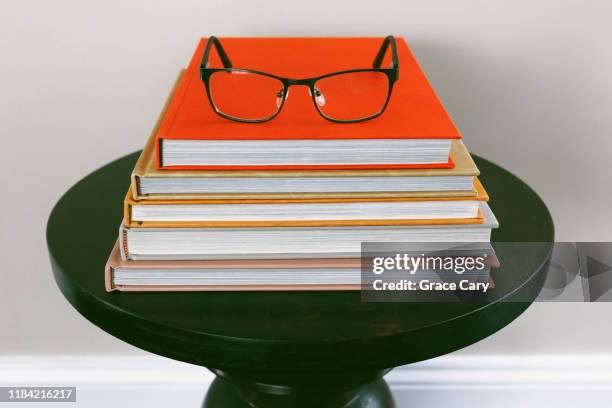 stack of books on side table with reading glasses on top - american literature stock pictures, royalty-free photos & images