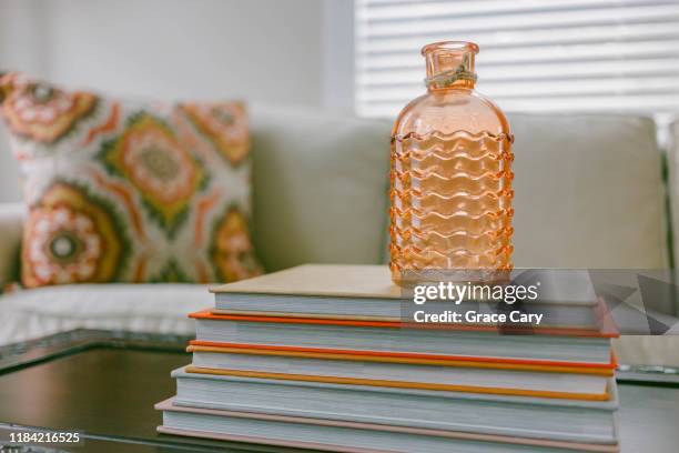 stack of books on coffee table with vase on top - coffee table books stockfoto's en -beelden