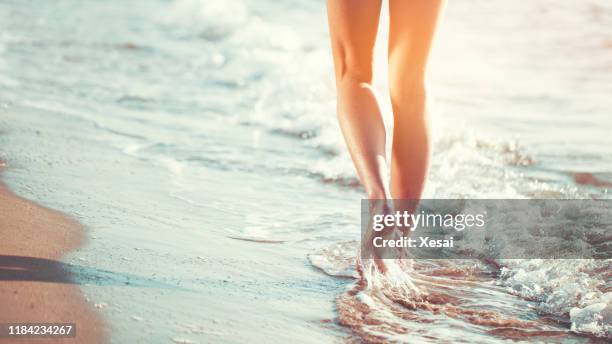 woman walking on the beach alone at sunset - human leg closeup stock pictures, royalty-free photos & images
