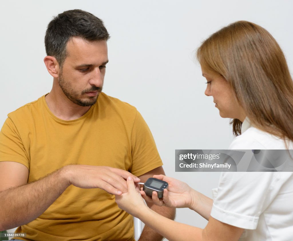 Female doctor doing a glucose test on a patient's finger
