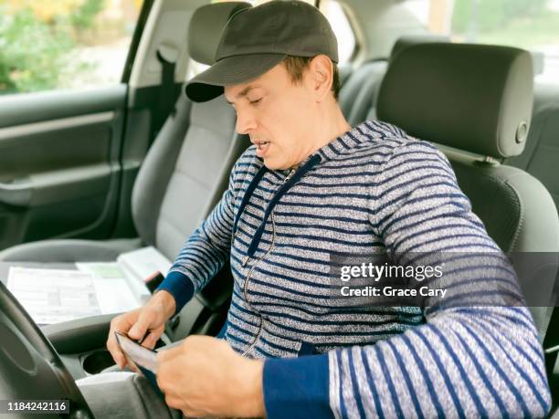 man reads paperwork in car - vehicle registration foto e immagini stock