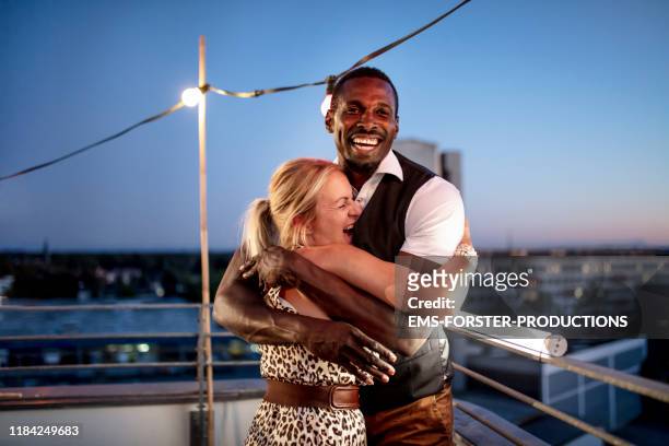 portrait of two friends hugging and embracing on a summer urban rooftop party - party in munich stock pictures, royalty-free photos & images