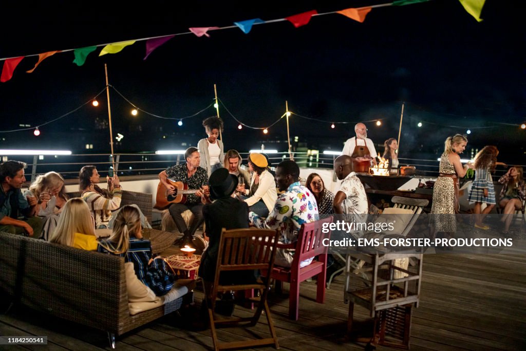 Large group of friends sitting together and enjoying a summer urban rooftop party in munich
