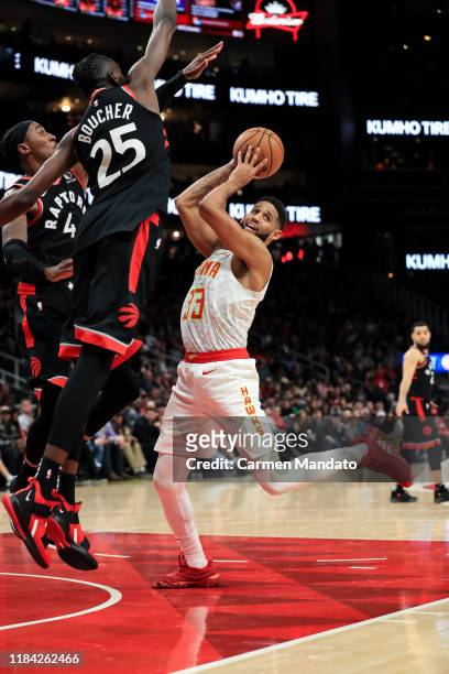 Allen Crabbe of the Atlanta Hawks looks to pass in front of defender Chris Boucher of the Toronto Raptors during the fourth quarter at State Farm...