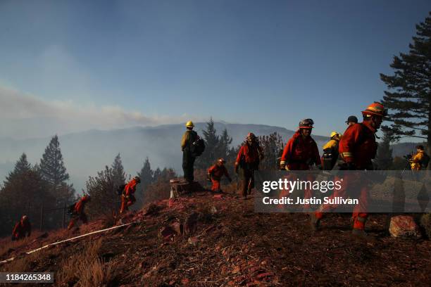 Firefighters stand in the yard of a home as they monitor air operations battling the Kincade Fire on October 29, 2019 in Healdsburg, California....