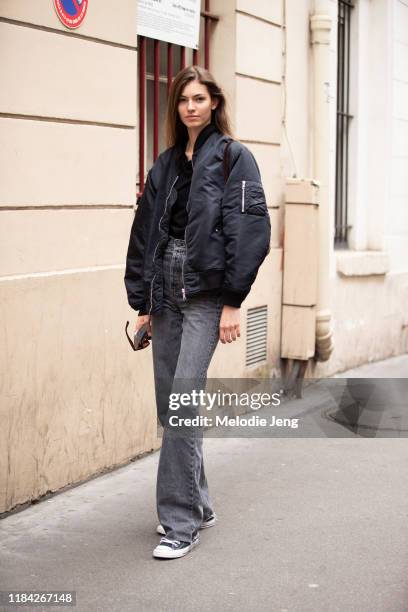 Model Alberte Mortensen wears a black bomber jacket, gray jeans, and black Converse shoes after the Olivier Theyskens show during Paris Fashion Week...
