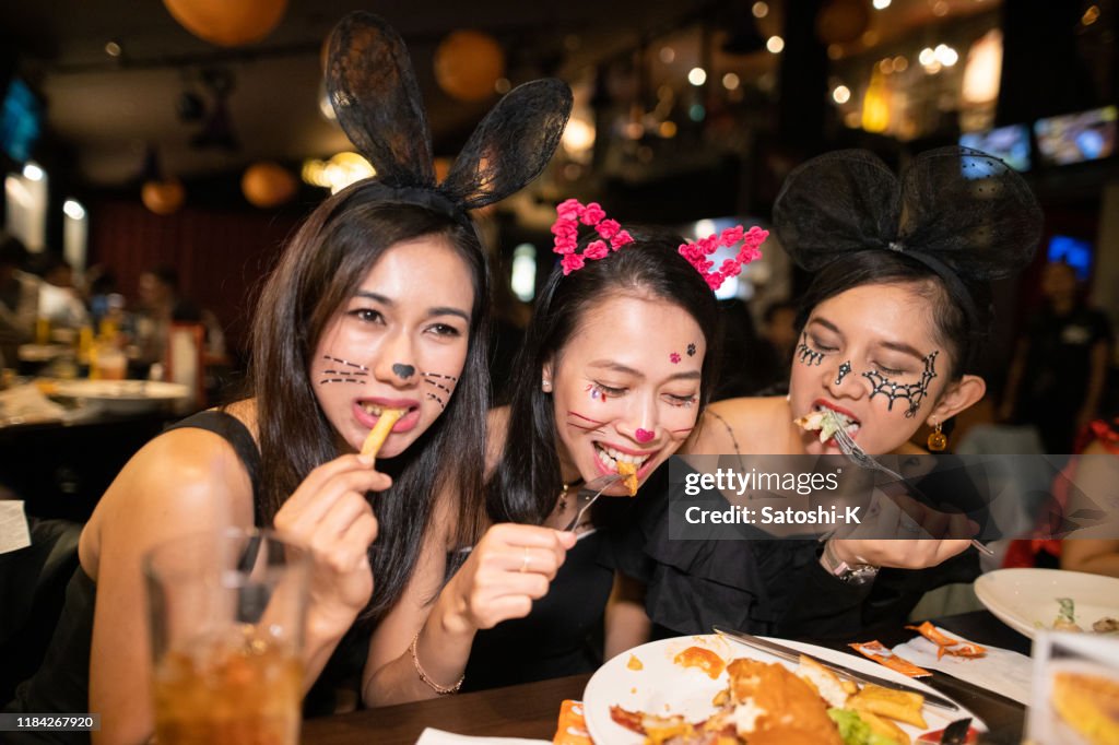 Asian women in halloween costume eating dinner at restaurant together
