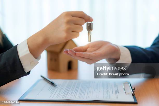 woman real estate agent handing over keys of new house giving house keys to man after signing rental lease contract of sale purchase agreement, concerning mortgage loan offer for and house insurance. - for lease sign stock pictures, royalty-free photos & images