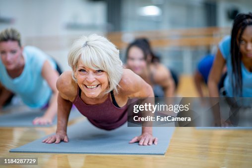 Senior Woman in Fitness Class in einer Planke Pose LächelndStock Foto Senior Woman in Fitness Class in einer Planke Pose LächelndStock Foto