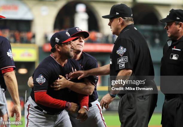 Dave Martinez of the Washington Nationals argues with umpire Gary Cederstrom as he is ejected and is held back by Chip Hale against the Houston...