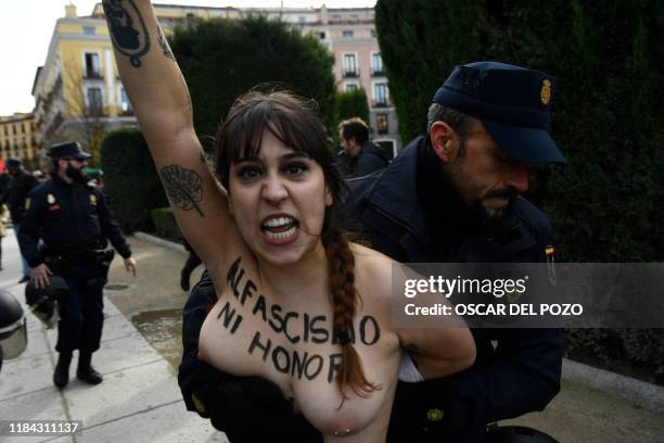 Spanish officer restrains a member of the feminist movement Femen as she protests against a far right demonstration marking the anniversary of the...