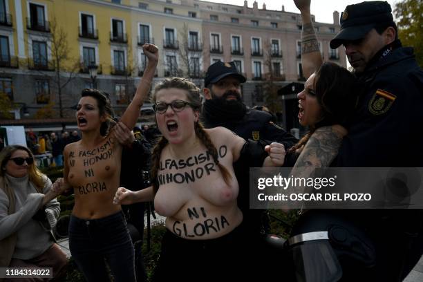 Spanish policemen restrain members of the feminist movement Femen as they protest against a far right demonstration marking the anniversary of the...