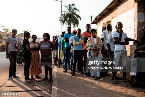 People wait outside a polling station in Bissau early on November 24 prior to voting as part of the presidential election in Guinea-Bissau. - Some...