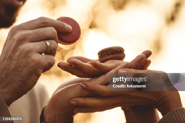 hands of woman offering two macaroons to man - sharing chocolate stock pictures, royalty-free photos & images