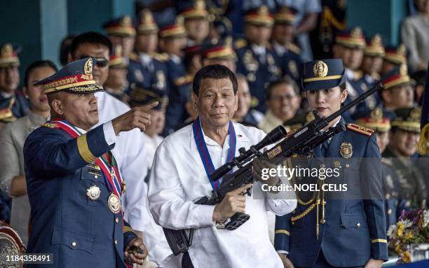 This file photo taken on April 19, 2018 shows Philippine President Rodrigo Duterte holding a Galil sniper rifle with outgoing Philippine National...