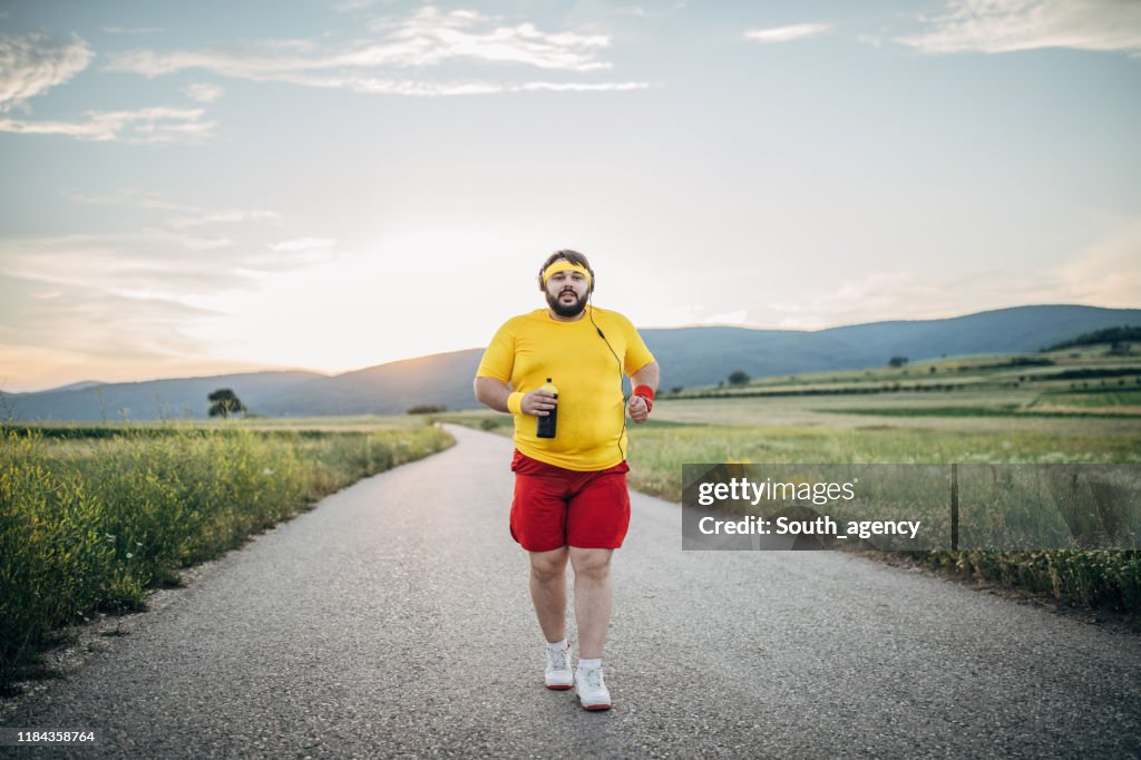 Overweight man jogging on the street in sunset