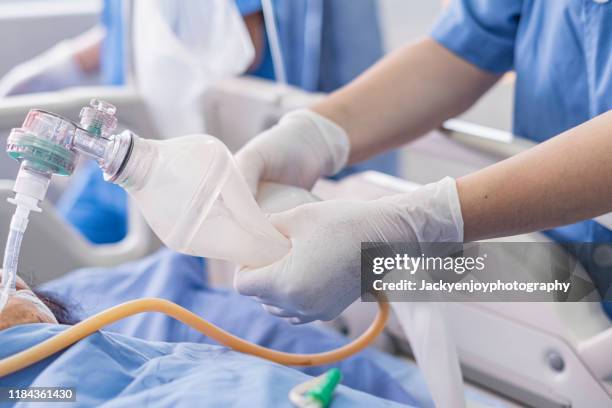 doctor holding oxygen ambu bag over patient given oxygen to patient by intubation tube in icu/emergency room - breathing device stock pictures, royalty-free photos & images