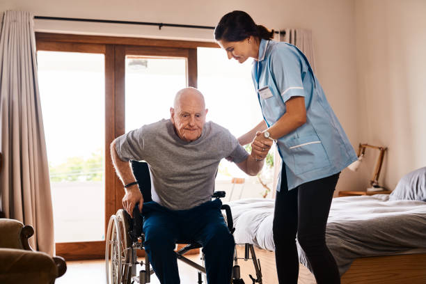 A home care giver helping an older man out of a wheelchair.