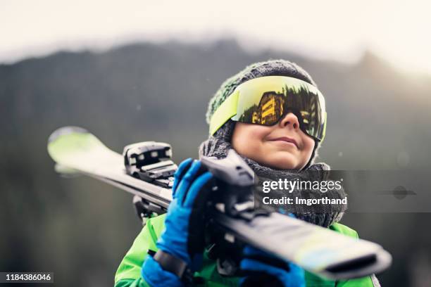 portrait of a little skier carrying his skis - kids skiing stock pictures, royalty-free photos & images