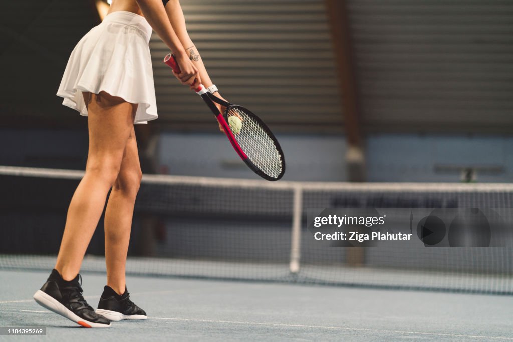 Kvinnor midja ner klädd i en Tennis Kjol, redo att tjäna bollen