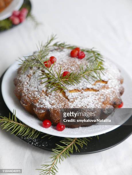 traditional christmas cake decorated with berries, icing sugar and green sprigs on a white table - cake table photos et images de collection