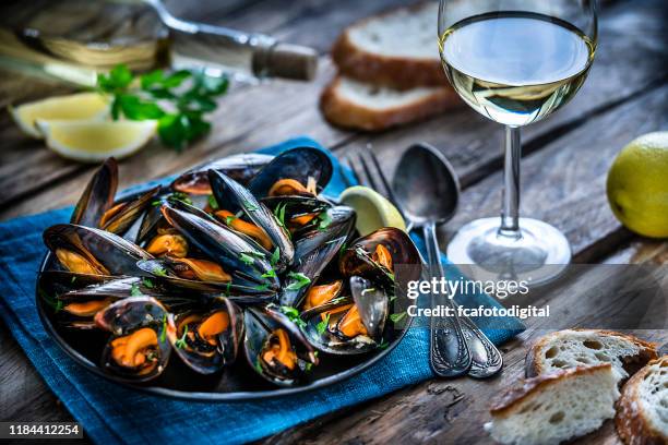 gedünste muscheln und weißwein auf rustikalem holztisch - clams cooked stock-fotos und bilder