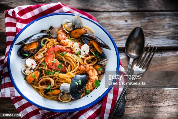 義大利食品：從上面在質樸的木桌上打海鮮義大利面 - 海產 個照片及圖片檔