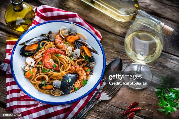 italienische küche: meeresfrüchte pasta und weißwein auf rustikalem holztisch - brown sauce stock-fotos und bilder