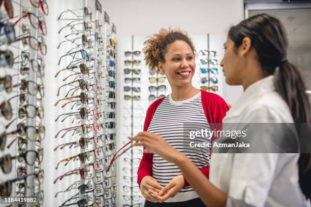 african american woman buying eyeglasses at a clinic - indian american woman stock pictures, royalty-free photos & images