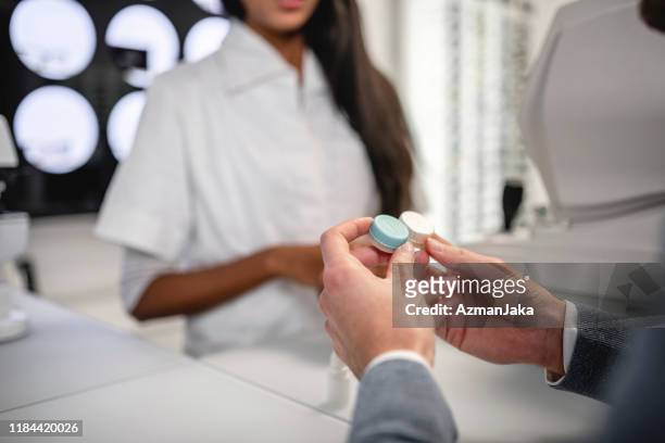 indian female doctor showing contact lenses case to her patient - contact lens stock pictures, royalty-free photos & images