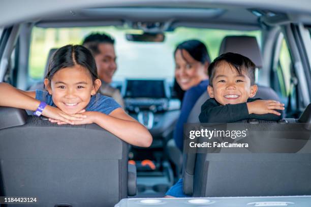 mixed race family of four road trip stock photo - road race car stock pictures, royalty-free photos & images