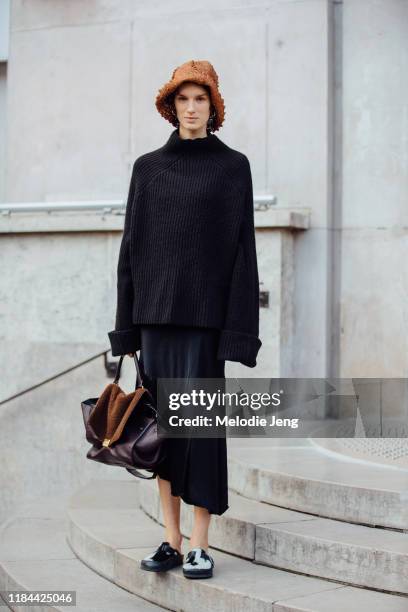 Model Marte Mei Van Haaster wears a brown woven hat, black knit top, black skirt, brown Celine trapeze bag, and black and white fur loafers after the...