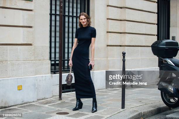 Model Lena Hardt wears a black form-fitting dress, brown bag, and black heeled boots after the Altuzarra show during Paris Fashion Week Spring/Summer...