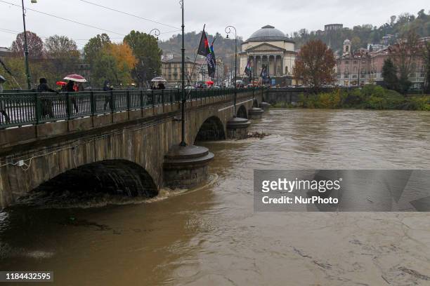 People stand by a flooded bank of the river Po in the city center of Turin on November 24, 2019 after its level rose overnight following heavy rain....
