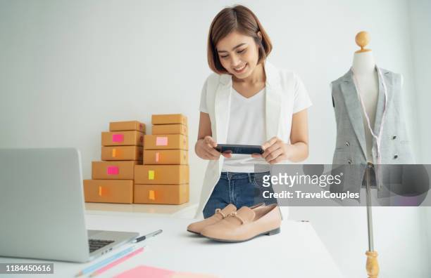 young women taking photo to shoes with cell telephone or smartphone digital camera for post to sell online on the internet and preparing pack product box. selling online ideas concept - e commerce asian stock pictures, royalty-free photos & images