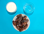 Date fruits, water and laban on blue background