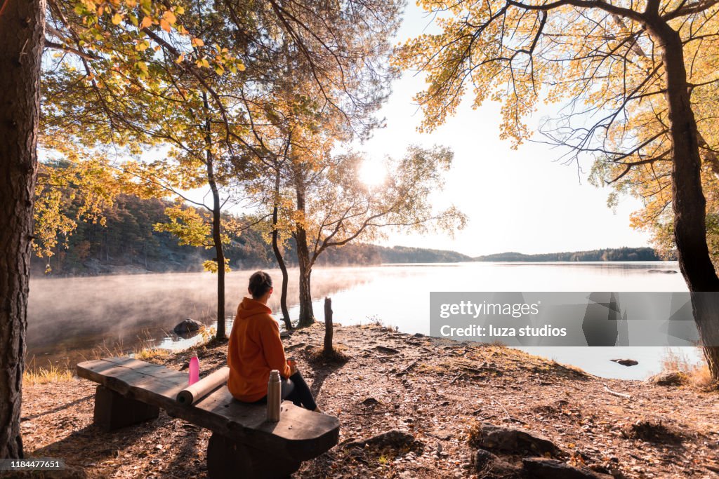 Woman drinking coffee outdoors by the lake