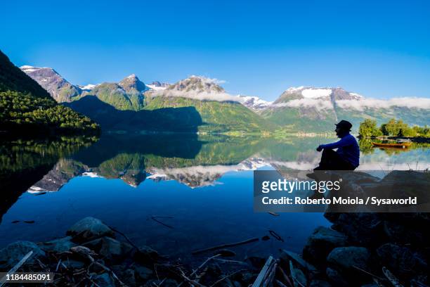 hiker admiring oppstrynsvatn lake, hjelle, norway - olden norwegen stock-fotos und bilder