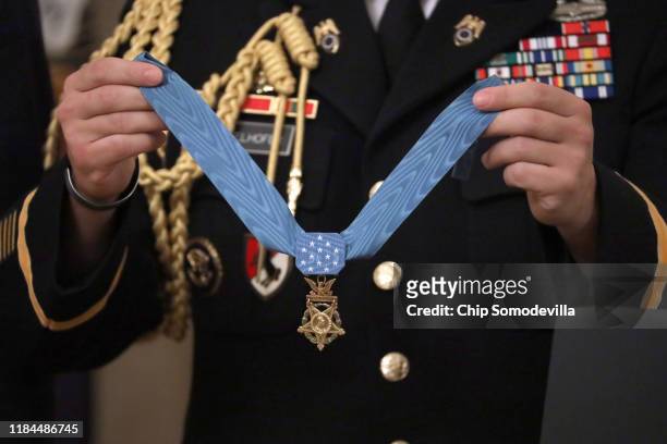 Military aide holds U.S. Army Master Sgt. Matthew Williams' Medal of Honor during a ceremony in the East Room of the White House October 30, 2019 in...