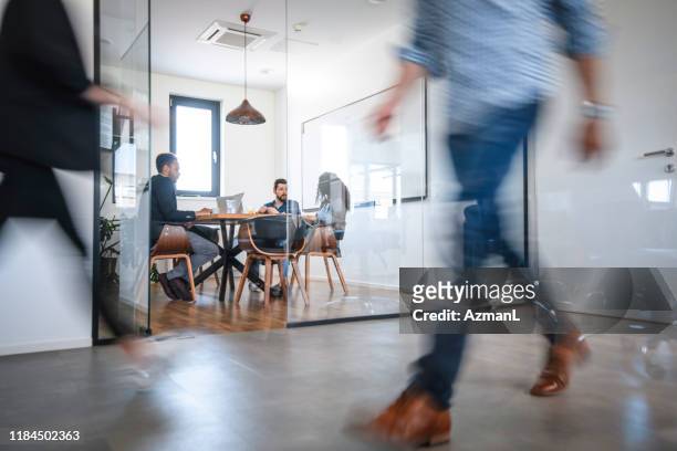 business colleagues in motion past office conference room - business casual walking stock pictures, royalty-free photos & images