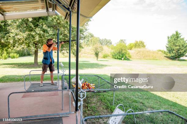 homem adulto que está na pista de acendimento e que pratica o tiro do skeet - clay pigeon shooting - fotografias e filmes do acervo