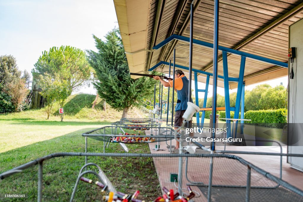Hombre adulto practicando skeet disparos en el campo de tiro