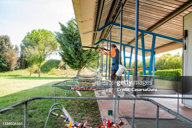 adult man practicing skeet shooting on shooting range - skeet shooting stock pictures, royalty-free photos & images