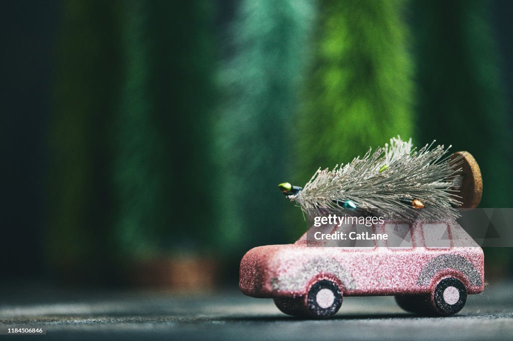 Pink car transporting Christmas tree. Christmas holiday background.